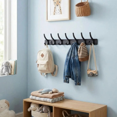 PatÚre Danielle noire à 8 crochets installée dans une entrée, avec sac à dos, veste en jean, bonnet et appareil photo suspendus. Décor mur bleu clair avec banc de rangement en bois et paniers en dessous.