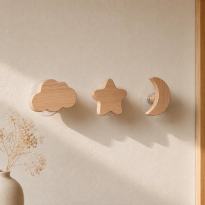 Ensemble de trois patères murales en bois clair en forme de nuage, d’étoile et de lune.