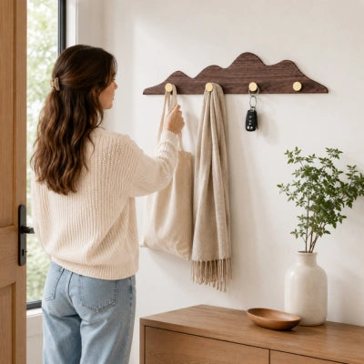 Femme récupérant un sac en toile sur une patÚre murale en bois brun, avec une écharpe et des clés suspendues à cÎté dans une entrée.